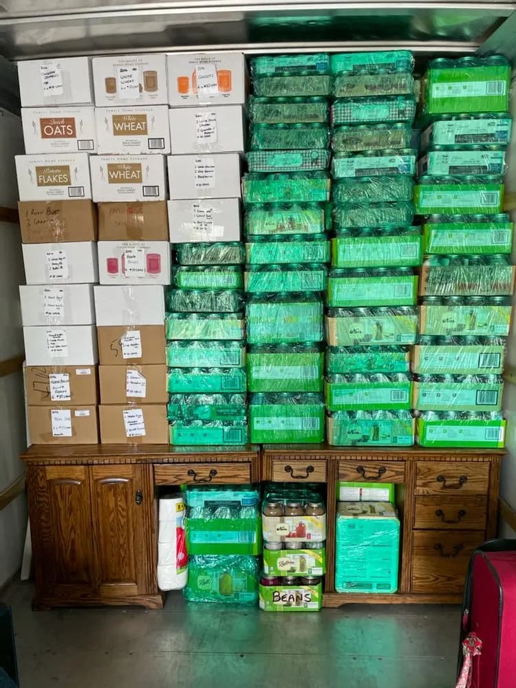 Shrink-wrapped canning jars and labeled pantry boxes stacked above wood cabinets in a moving truck