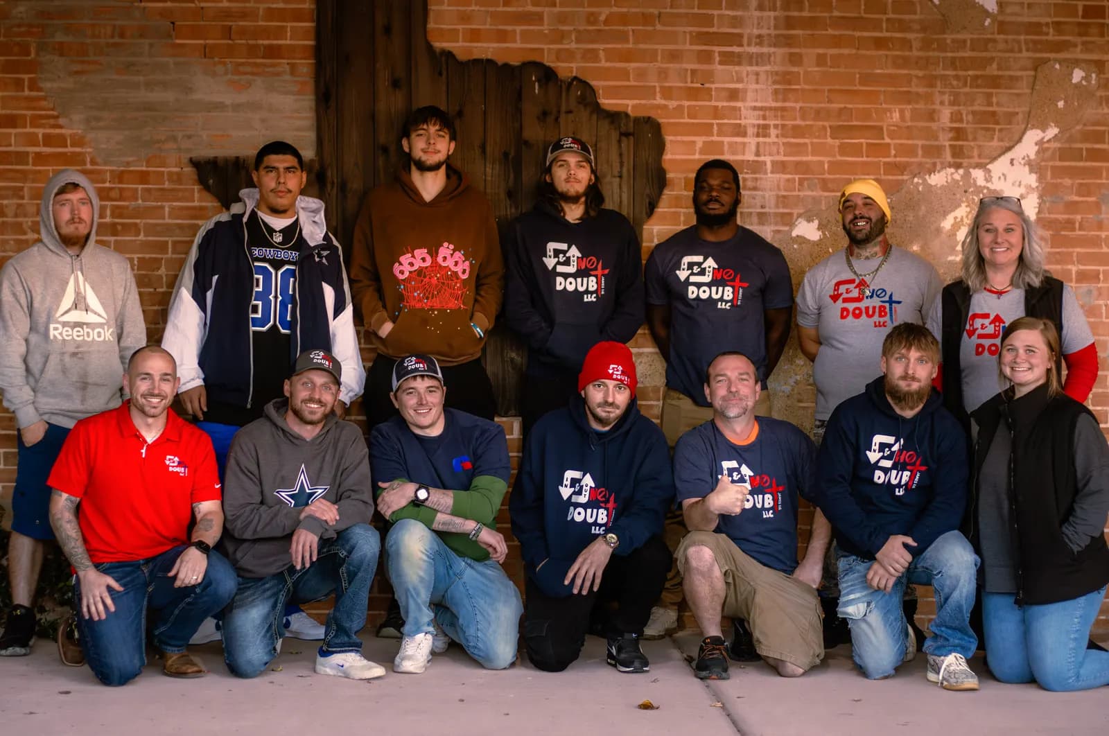 The In & Out No Doubt moving team in logo shirts posed in front of a wooden Texas plaque