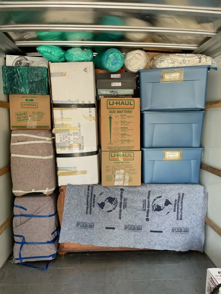 Neatly packed moving truck with stacked boxes, labeled blue totes, and blanket-wrapped furniture